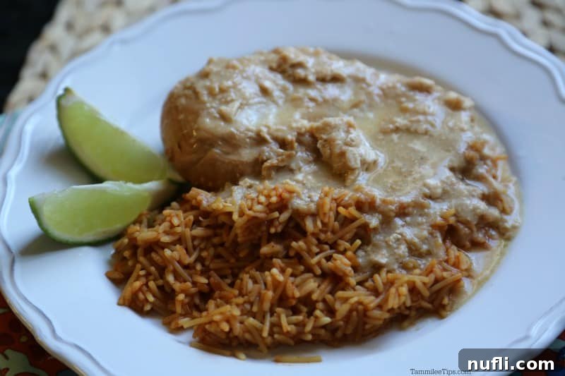 Close-up of succulent tequila chicken and fluffy rice served on a white plate, beautifully garnished with vibrant lime slices, ready to be enjoyed.