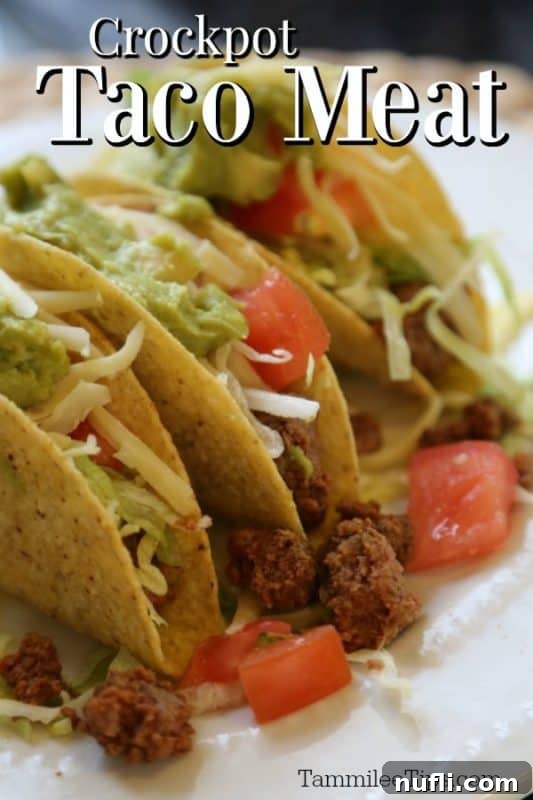 Crockpot Taco Meat over three tacos with ground beef, lettuce, and tomatoes