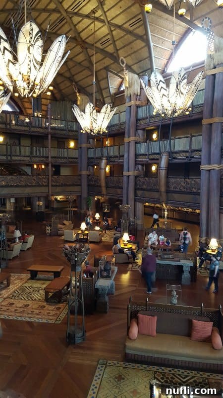 Large, ornate chandeliers with African-inspired design hanging in the majestic, high-ceilinged lobby of Animal Kingdom Lodge