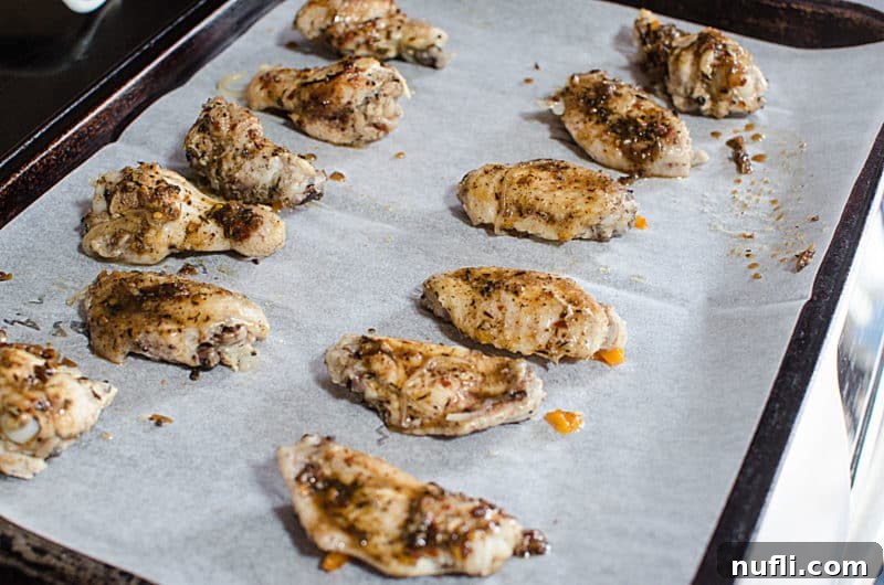 Crispy jerk chicken wings perfectly broiled and arranged on a parchment-lined baking sheet, ready to be served