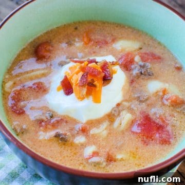 Cheeseburger soup garnished with sour cream, cheese, and bacon in a bowl