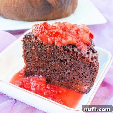Delicious Slow Cooker Chocolate Strawberry Cake on a white plate with strawberry sauce drizzled over it, ready to be served.