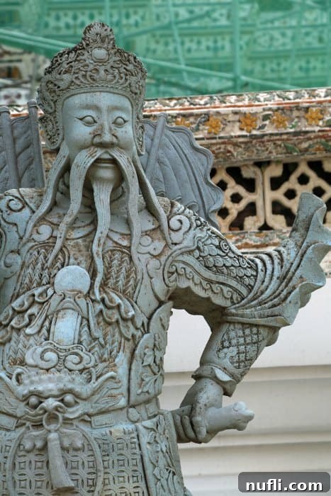 Detailed statue of a Chinese guard figure at the entrance to Wat Arun's terraces