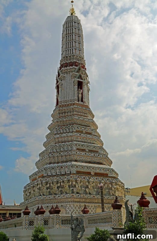 The iconic central prang of Wat Arun, Temple of Dawn, bathed in sunlight, Bangkok