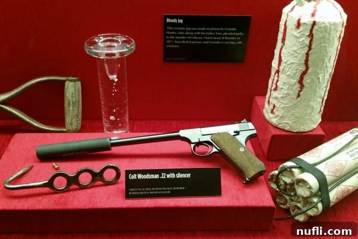 Historic mob weapons on display, including a Colt Woodsman .22 with a silencer, offering a chilling glimpse into the tools of the trade