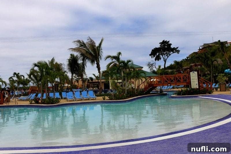 Blue chairs and palm trees surrounding a pool area in Amber Cove