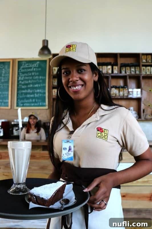 Waitress wearing an El Cibao shirt holding a tray with cake and coffee