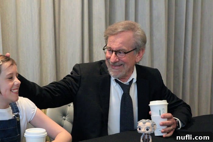 Steven Spielberg in deep thought at a press conference, with a Starbucks cup nearby, discussing his filmmaking approach for The BFG.