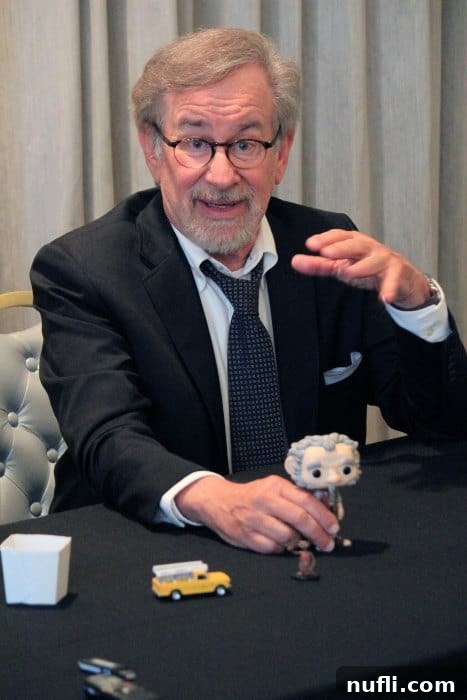 Steven Spielberg with a bobblehead at a movie press event, engaging with questions about his career and The BFG.