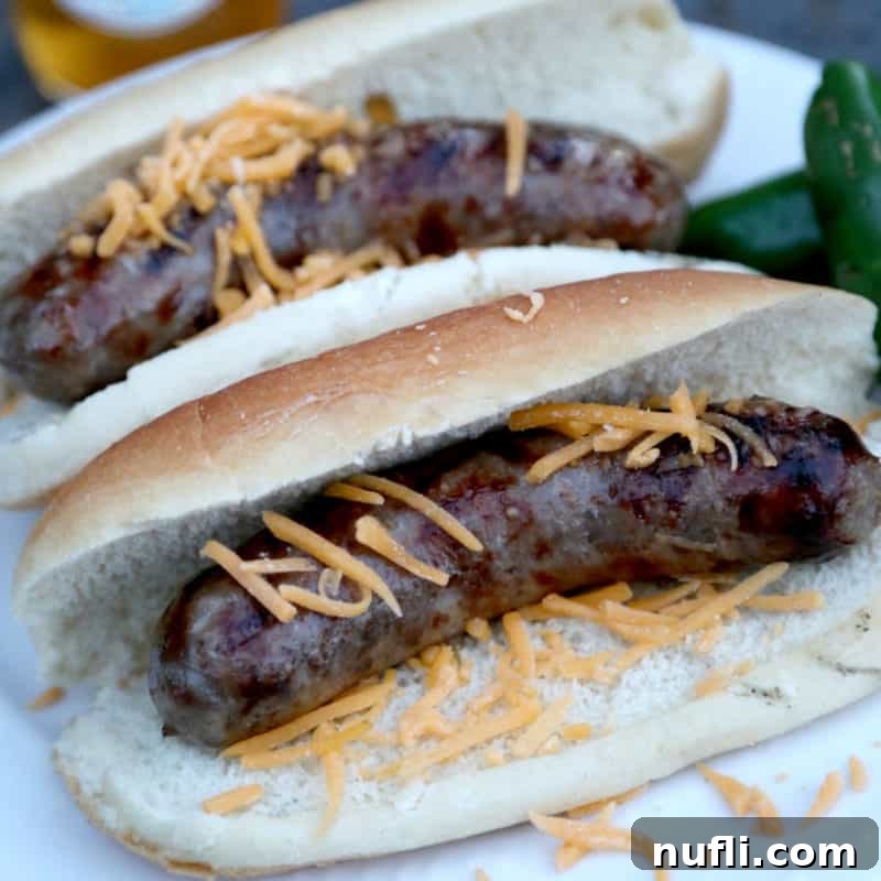 Bold Jalapeno Beer Brats 5 Two jalapeno beer brats on buns with shredded cheese and a side of peppers