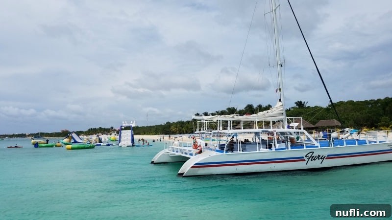 The Fury Catamaran anchored near a private beach in Cozumel, surrounded by fun water toys like paddleboards and inflatables.