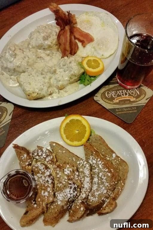 Two plates of hearty breakfast: one with golden French toast, the other with classic biscuits and gravy, accompanied by crispy bacon.