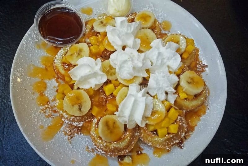 Fluffy waffle generously topped with sliced bananas and a dollop of fresh whipped cream, ready to be enjoyed for breakfast.