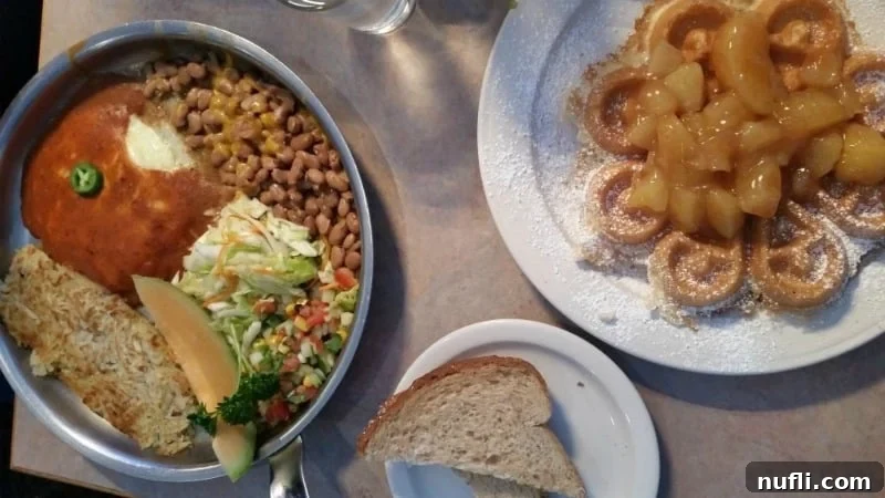 A unique breakfast plate featuring a waffle topped with apples, beans, eggs, and hash browns, alongside a plate of buttered toast.