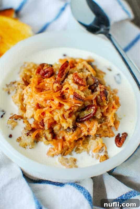 carrot cake oatmeal in a white bowl next to a spoon on a cloth napkin
