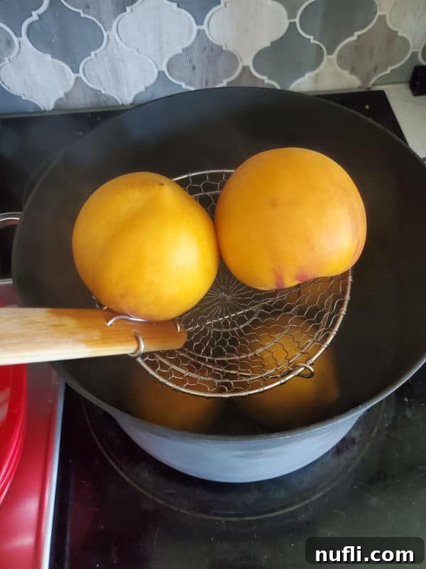 Luscious Crockpot Peach Butter 4 Peaches being blanched in a pot of boiling water using a spider strainer.