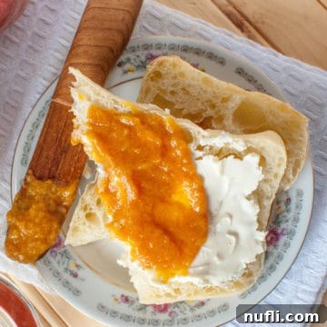 Luscious Crockpot Peach Butter 6 Crockpot Peach Butter on a piece of bread next to a wooden knife on a white plate
