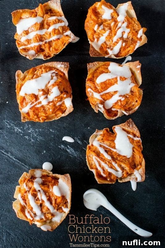 Buffalo chicken wontons served on a dark board with a small spoon of ranch dressing, highlighting their party appeal.