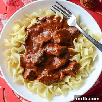 Set It and Forget It Goulash 6 crockpot goulash on a white plate with egg noodles and a fork