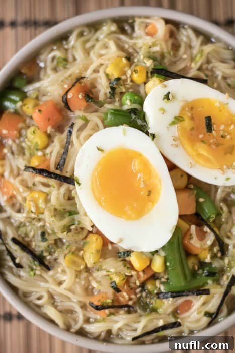 A perfectly halved hard-boiled egg with a creamy yolk resting atop a bowl of quick ramen.