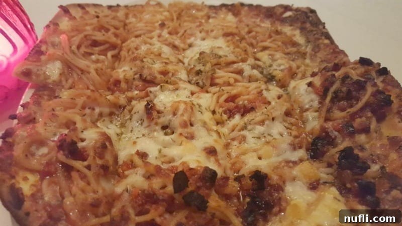 A unique and appetizing Spaghetti pizza, showcasing a creative fusion of two comfort foods