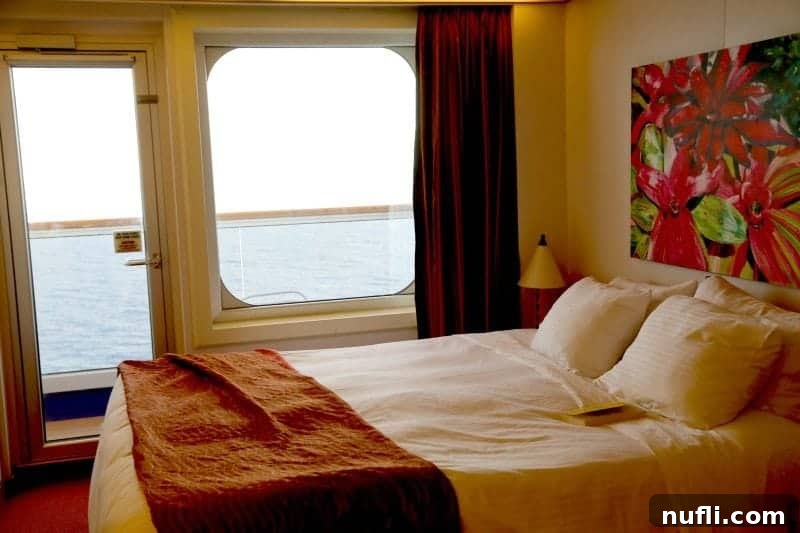 A comfortable Carnival Magic stateroom with a well-made bed overlooking a private balcony and the vast ocean beyond.