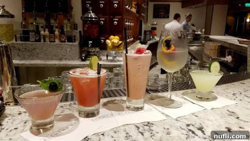 A beautifully arranged row of Alchemy Bar cocktails, each presented on a napkin, showcasing the artistry of the mixologists.