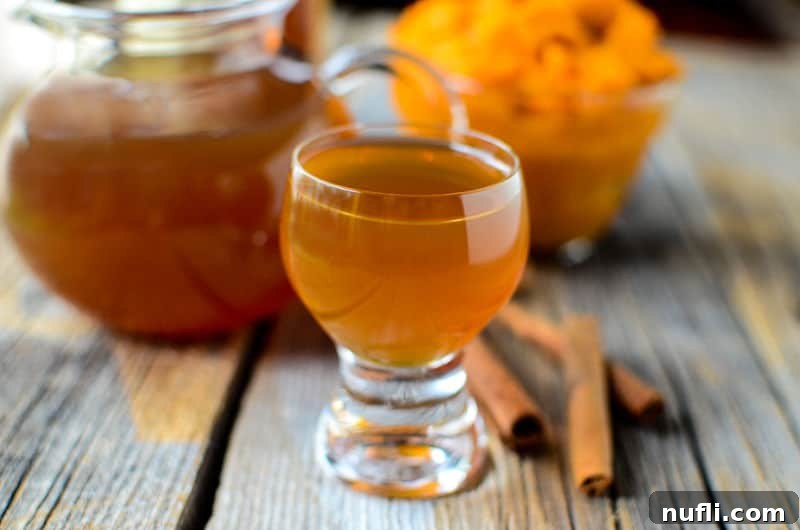 Cozy Slow Cooker Pumpkin Spice Liqueur 4 Small glass of slow cooker pumpkin spice liqueur on a wooden background with pumpkin in the background