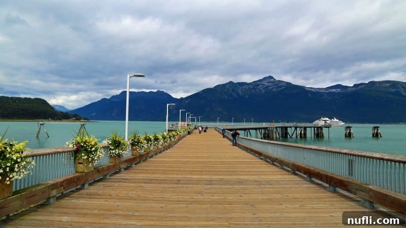 long dock with a boat in the distance on glacial water 