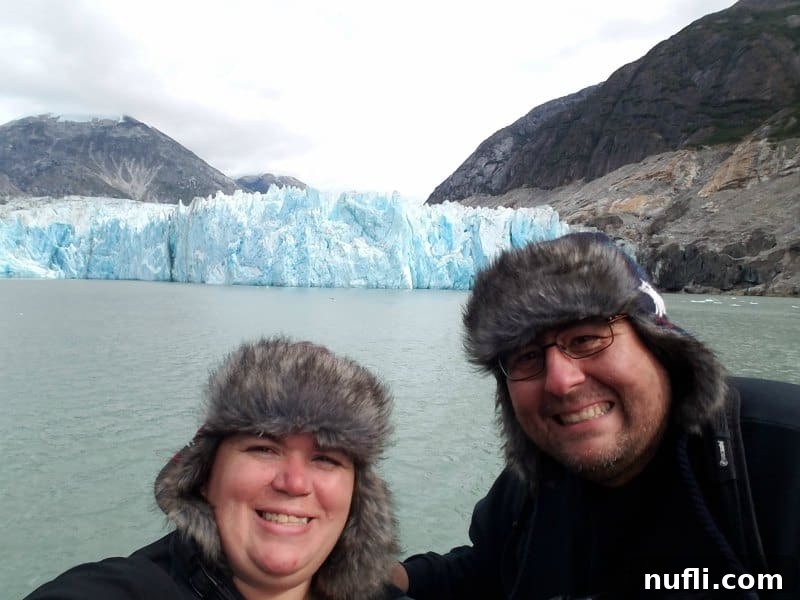 Tammilee and John smiling on a boat in front of a glacier in Alaska 