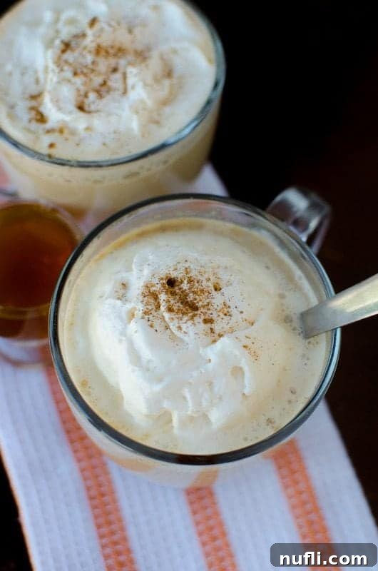 2 Crockpot pumpkin spice lattes in glass mugs on a white and orange towel. 