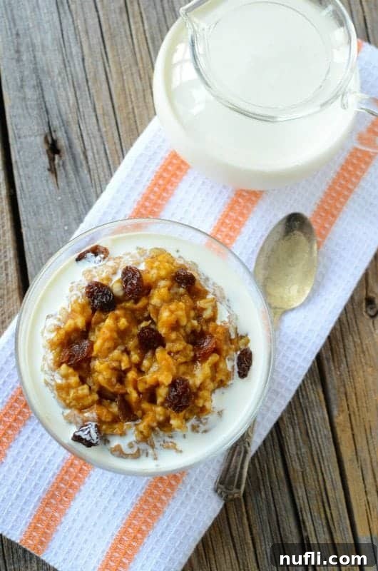 Overnight Crock Pot Pumpkin Oatmeal 3 Individual serving of pumpkin oatmeal in a glass jar, next to a spoon and a small jar of milk, highlighting its grab-and-go convenience.
