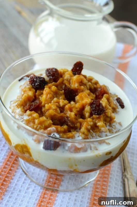 Overnight Crock Pot Pumpkin Oatmeal 4 Close-up of pumpkin oatmeal in a glass jar, generously topped with plump raisins, showcasing a delicious serving suggestion.