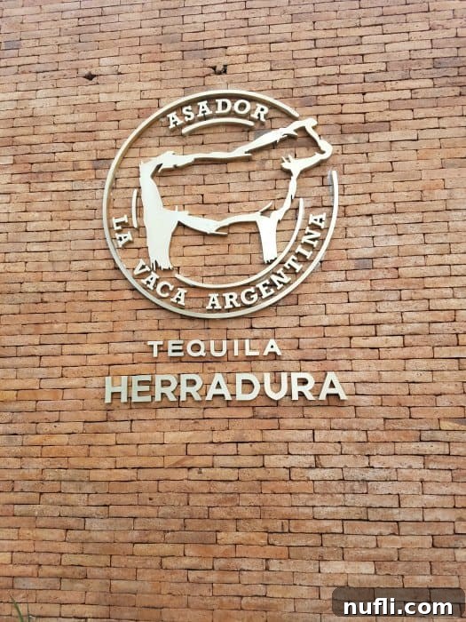 Asador La Vaca Argentina Tequila Herradura sign with a cow motif on a brick wall, indicating an upscale steakhouse.