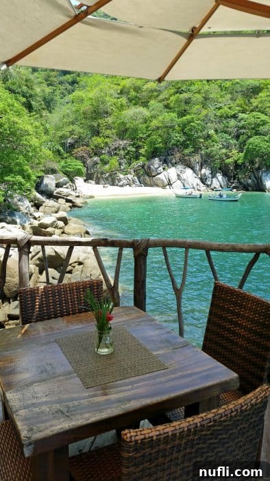 Table and chairs at the edge of Ocean Grill restaurant, overlooking tropical water, inviting relaxation.
