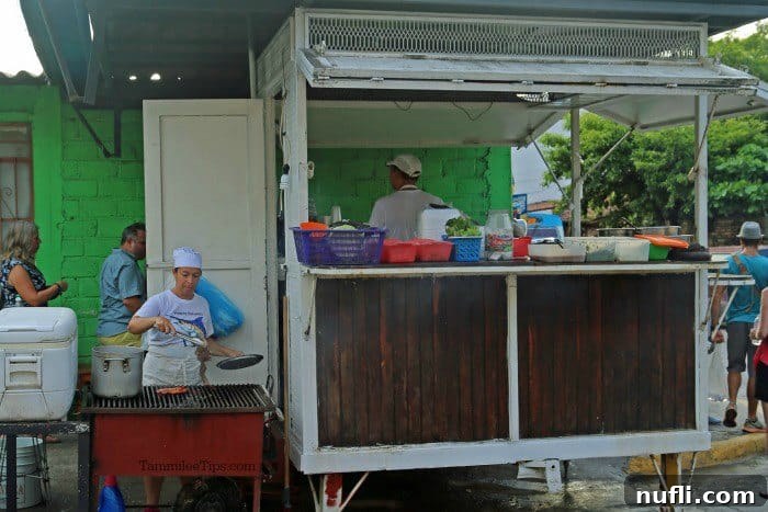 Taco stand with people working by the grill and behind the counter, bustling with activity.