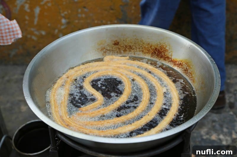 Churro cooking in hot oil, a classic Mexican sweet treat.