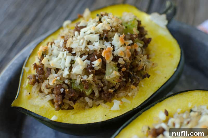 Close-up of a beautifully stuffed acorn squash with sausage, rice, and melted Parmesan, on a rustic background.