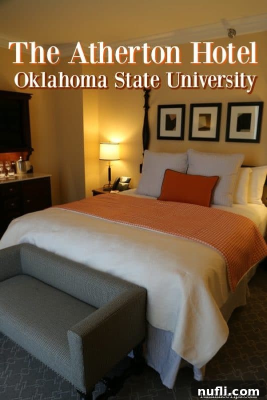 Oklahoma State University's Atherton Hotel in Stillwater 2 The Atherton Hotel guest room featuring a plush bed with an orange accent pillow, showcasing the hotel's luxurious and tastefully designed interior.