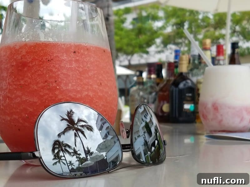 Sunglasses reflecting palm trees next to a strawberry margarita 
