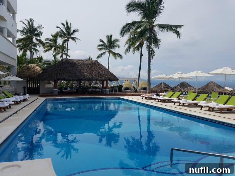 pool with palm trees near it and pool deck seating 