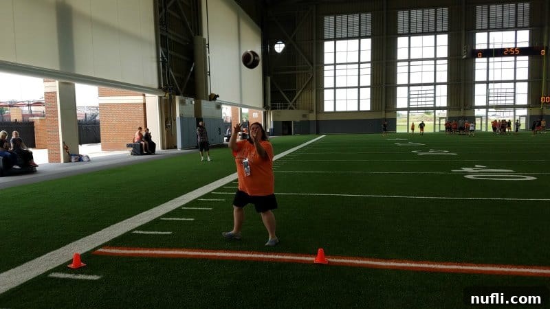 Tammilee mid-action, attempting to catch a football during a drill at Football 101.