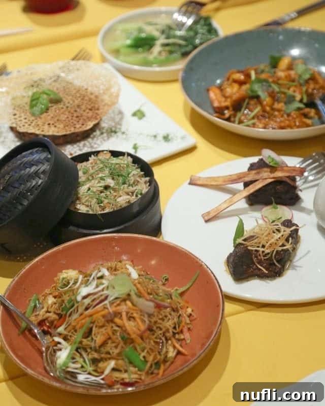 Rable covered in plates and bowls with noodles, meats, and vegies 