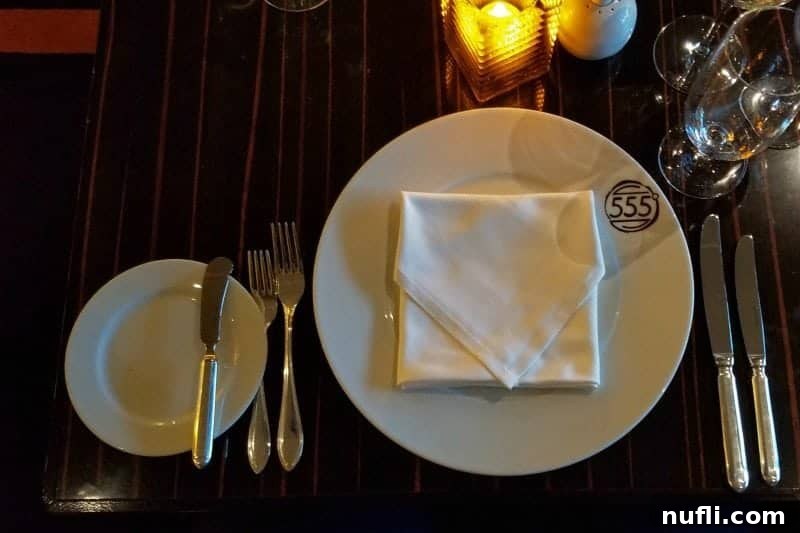 An elegantly set table at Fahrenheit 555, featuring pristine plates and dishware, awaiting the arrival of gourmet cuisine.