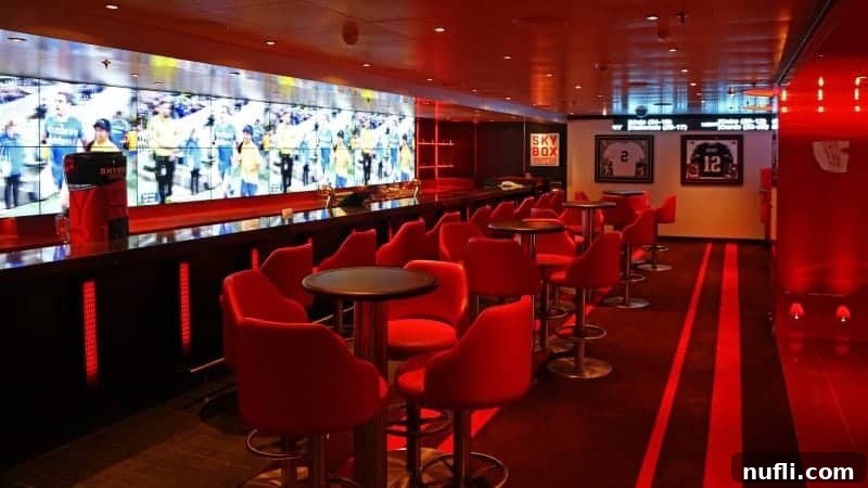 The energetic SkyBox Sports bar, featuring comfortable red chairs, modern tables, and a massive screen displaying multiple televisions for ultimate sports viewing.