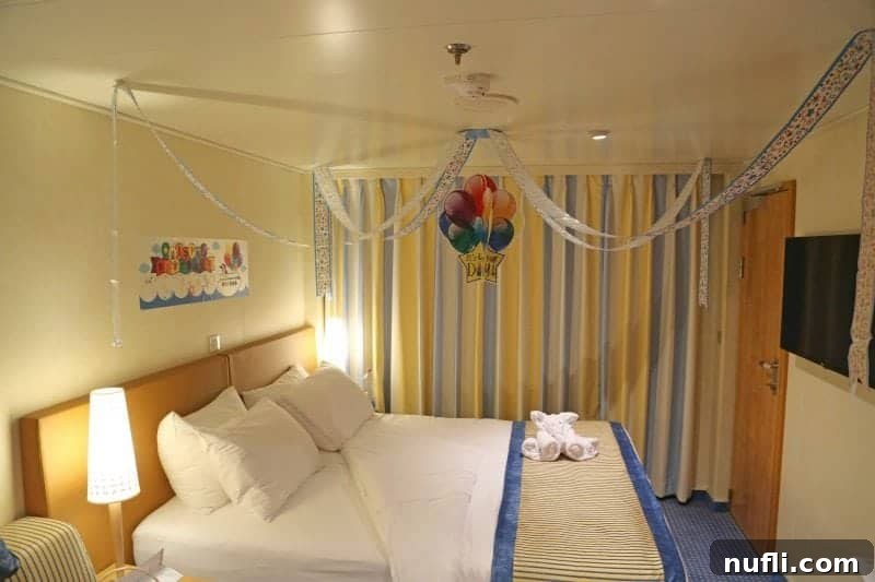 A festive Carnival Vista stateroom, beautifully decorated for a birthday celebration, complete with a charming towel animal gracing the bed.