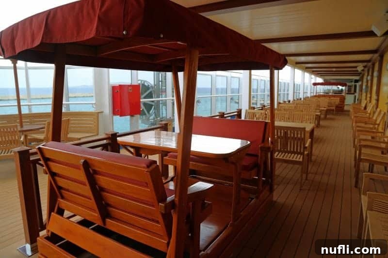 A charming swinging bench positioned invitingly next to a table on the open deck of the Carnival Vista, perfect for relaxation.