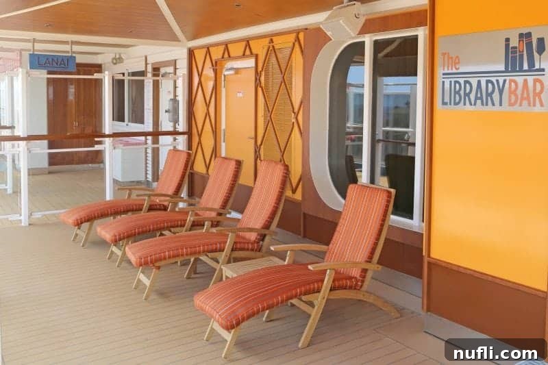 The Library Bar sign, prominently displayed near comfortable deck chairs with vibrant orange cushions, inviting guests to relax.
