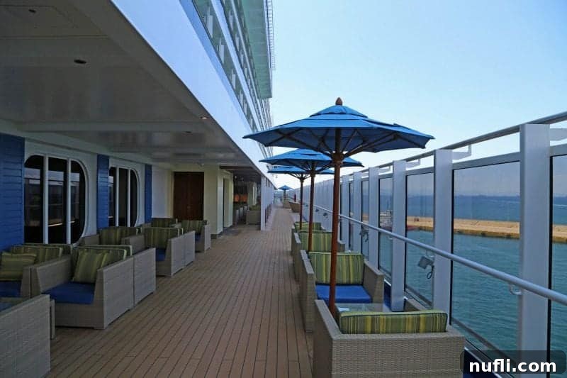 outdoor deck with chairs and blue umbrellas on the Carnival Vista 