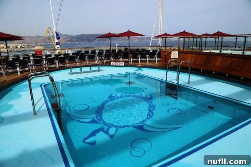 A spacious swimming pool featuring a charming turtle mural on its bottom, surrounded by comfortable lounge chairs for sunbathing.